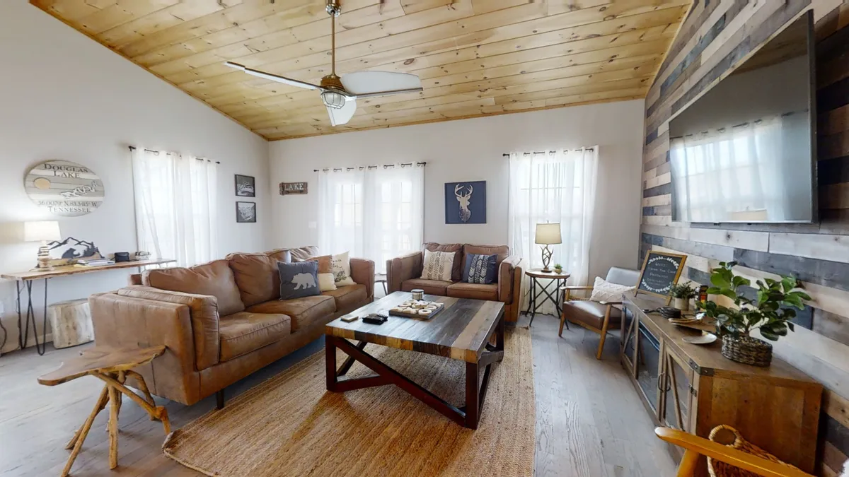 A welcoming living room featuring leather sofas arranged around a wooden coffee table, with decorative wall art and a large window letting in natural light. The space is designed for comfort and relaxation, ideal for group gatherings or unwinding after a day of adventure.