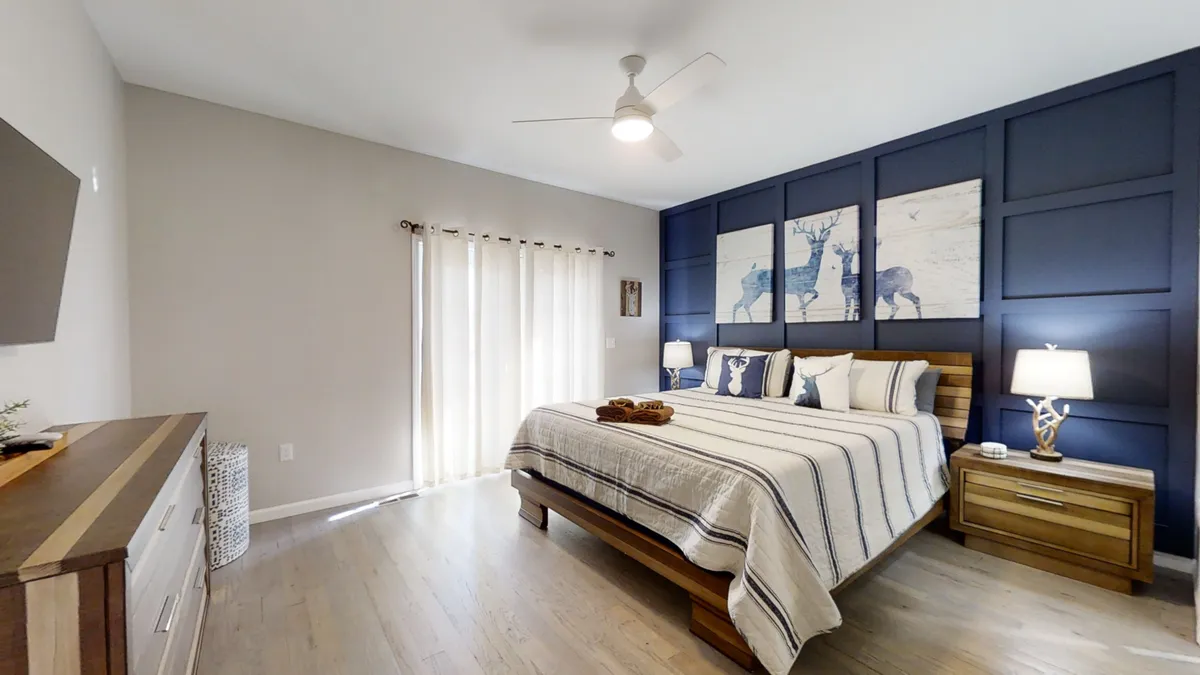 A serene bedroom featuring a neatly made bed with soft linens, a nightstand with a lamp, a dresser, and calming wall art. The space is uncluttered, inviting, and filled with soft natural light, evoking a sense of peace and relaxation.