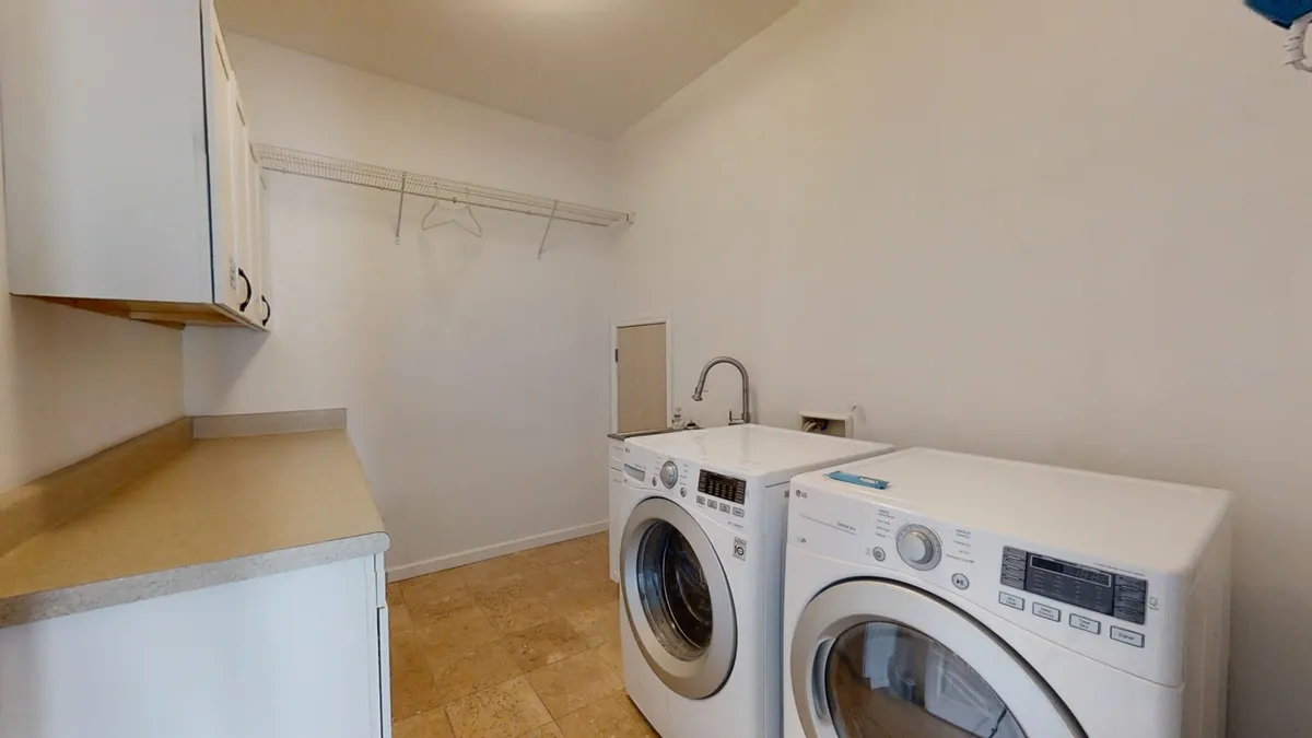 A tidy laundry room equipped with a washing machine, dryer, and countertop for folding clothes. The setup is practical and efficient, supporting extended stays and family convenience.