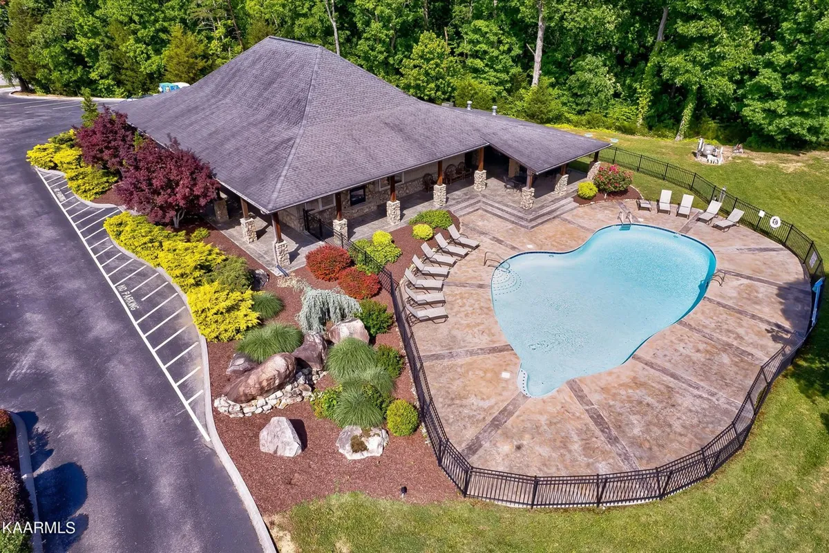 This exterior shot captures the sparkling community swimming pool surrounded by a beautifully landscaped garden and an attractive stone building. The inviting setting hints at opportunities for swimming, sunbathing, and social gatherings within the gated resort community.